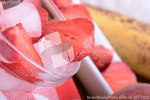 Image of A slice of red strawberry on glass plate with bananas and peach, health food concept