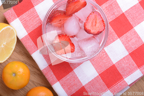 Image of A slice of red strawberry on glass plate with lemon and mandarin in party theme background