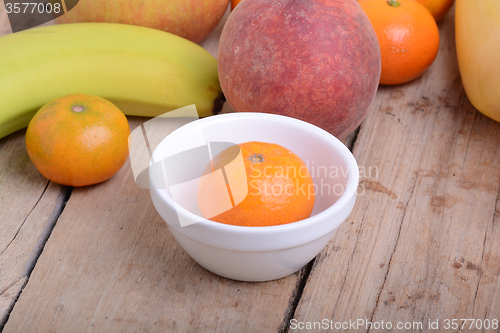 Image of Mandarin Apples Bananas Peach on wooden plate