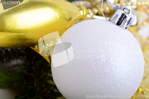 Image of festive golden christmas decoration, candles, white balls, green fir tree branch, close up