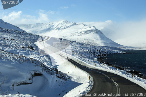 Image of Snowy and icy road with volcanic mountains in wintertime