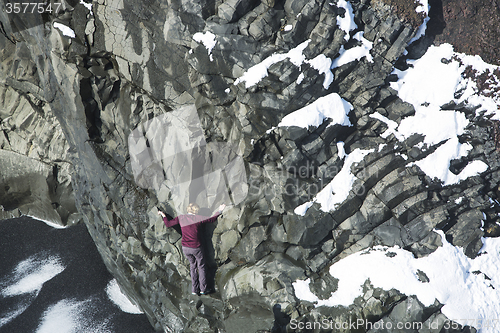 Image of Woman climbing up basalt rocks, Iceland