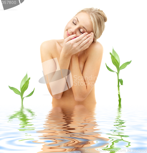 Image of happy blonde with flower petals and green plants in spa