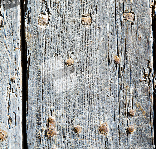 Image of metal nail dirty stripped paint in the brown   red wood door and