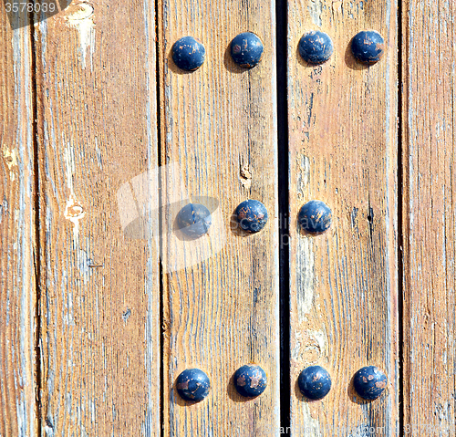 Image of metal nail dirty stripped paint in the brown   red wood door and