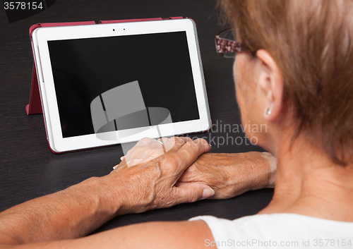 Image of Senior lady relaxing and reading the screen of her tablet