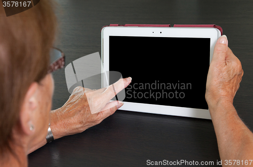 Image of Senior lady relaxing and reading the screen of her tablet