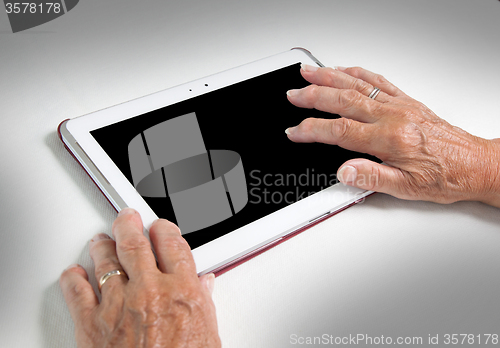 Image of Hands of senior lady relaxing and reading the screen of her tabl