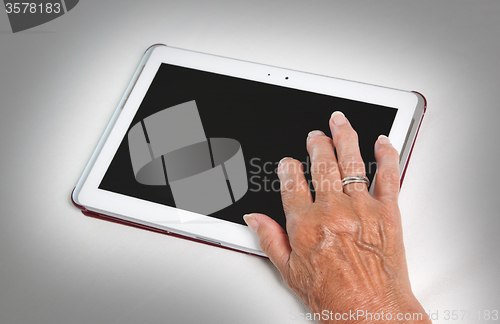 Image of Hand of senior lady relaxing and reading the screen of her table