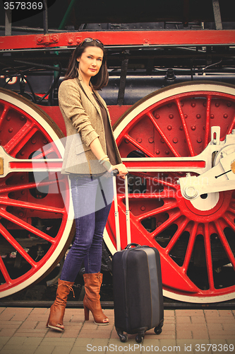 Image of woman with luggage near the old steam locomotive