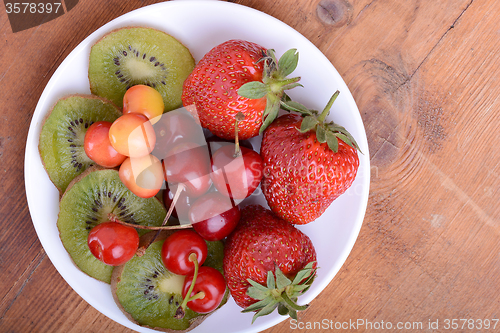 Image of health fruit with cherry, strawberry, kiwi on wooden plate