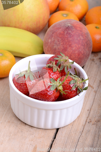 Image of Bananas apple mandarin peach strawberry on wooden background as health food concept