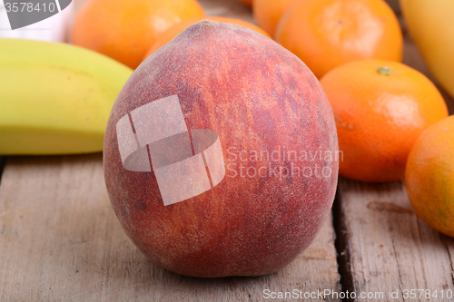 Image of Bananas apple mandarin peach strawberry on wooden background as health food concept