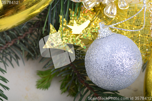 Image of festive golden christmas decoration, candles, white balls, green fir tree branch, close up