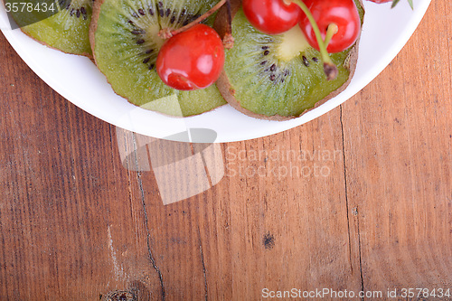 Image of health fruit with cherry, kiwi slices on wooden plate