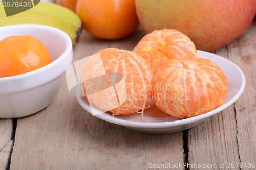 Image of Bowls of slices mandarin with apple on rustic wooden background