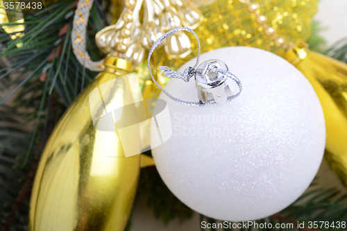 Image of festive golden christmas decoration, candles, white balls, green fir tree branch, close up
