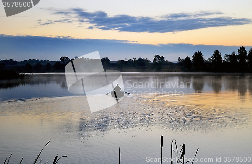 Image of A fisherman in a boat sailing in the morning mist