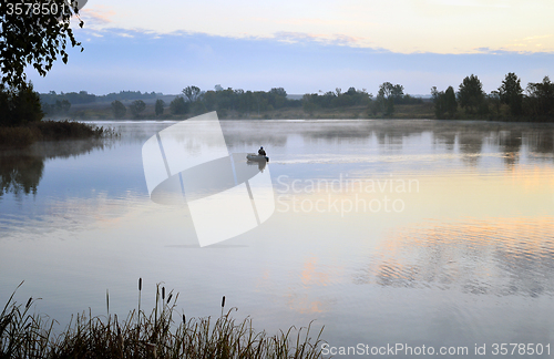 Image of A fisherman in a boat sailing in the morning mist