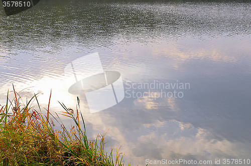 Image of Autumn water background with reflection of clouds in water and g