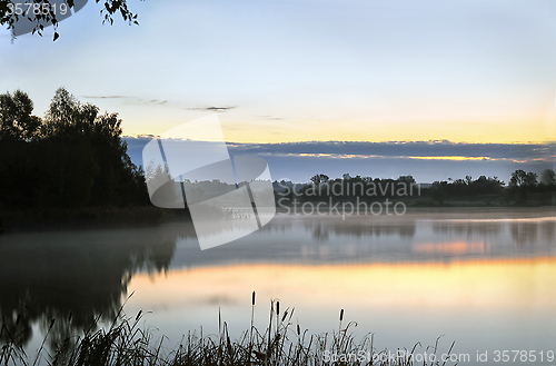 Image of The morning landscape with sunrise over water in the fog