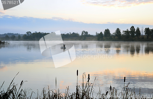 Image of A fisherman in a boat sailing in the morning mist