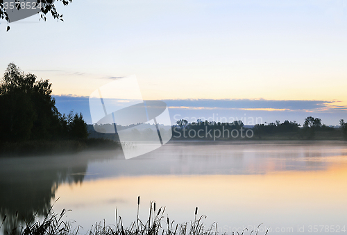 Image of The morning landscape with sunrise over water in the fog