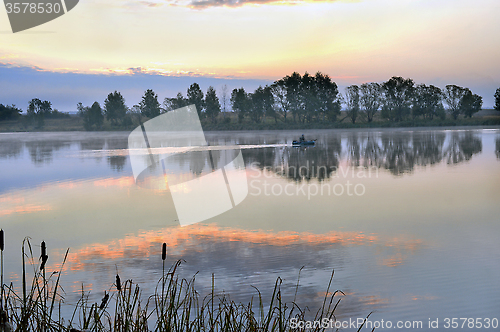 Image of A fisherman in a boat sailing in the morning mist