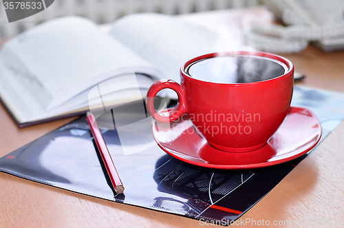 Image of Red cup of coffee on the desk in the office