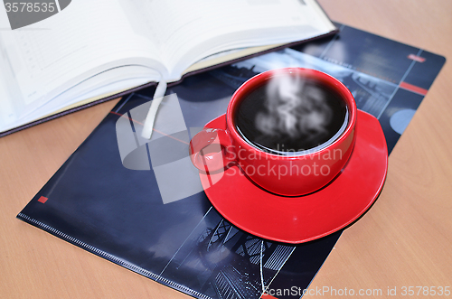 Image of Red cup of coffee on the desk in the office