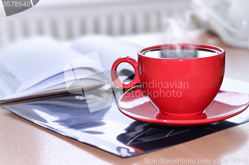 Image of Red cup of coffee on the desk in the office