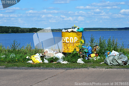 Image of Overflowing barrel with rubbish and waste disposal on the waterf