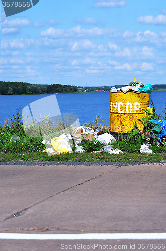 Image of Overflowing barrel with rubbish and waste disposal on the waterf
