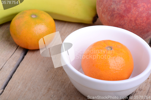 Image of Bananas apple mandarin peach strawberry on wooden background as health food concept