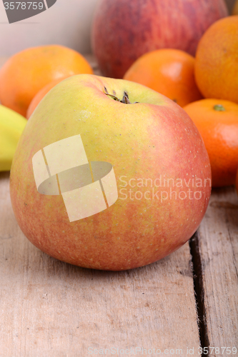 Image of Bananas apple mandarin peach strawberry on wooden background as health food concept