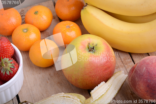 Image of Bananas apple mandarin peach strawberry on wooden background as health food concept