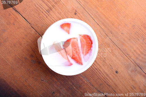Image of Slice of pie with strawberry on white plate, milk drink, wooden background. Top view