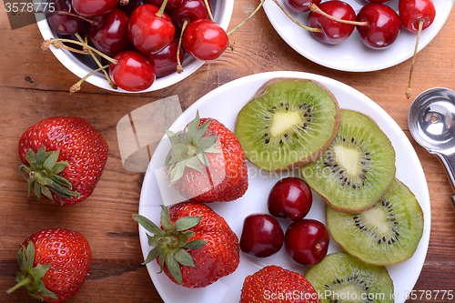 Image of fruit with cherry, strawberry, kiwi on wooden plate