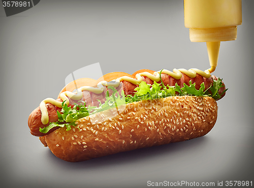 Image of Hot dog with pouring mayonnaise
