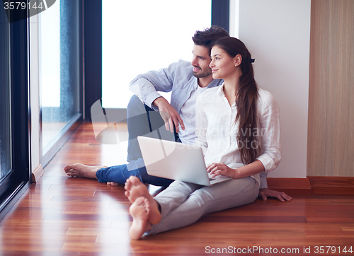 Image of relaxed young couple working on laptop computer at home