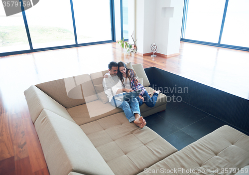 Image of relaxed young couple working on laptop computer at home