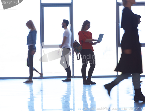 Image of student girl standing with laptop, people group passing by