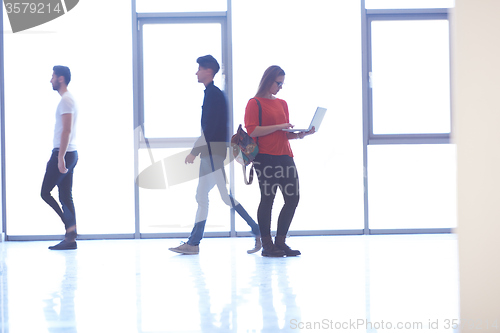 Image of student girl standing with laptop, people group passing by