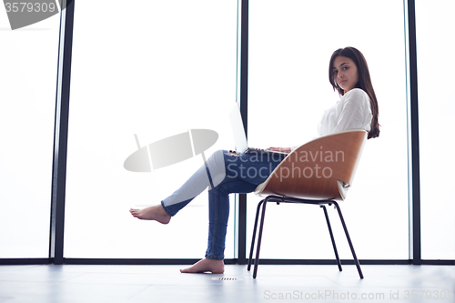 Image of relaxed young woman at home working on laptop computer