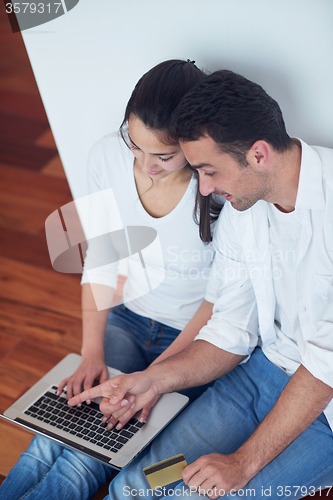 Image of relaxed young couple working on laptop computer at home