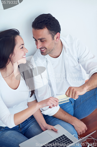 Image of relaxed young couple working on laptop computer at home