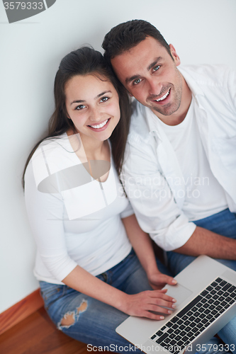 Image of relaxed young couple working on laptop computer at home