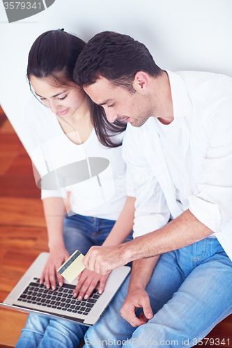 Image of relaxed young couple working on laptop computer at home