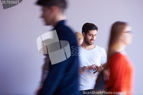 Image of student working on tablet, people group passing by