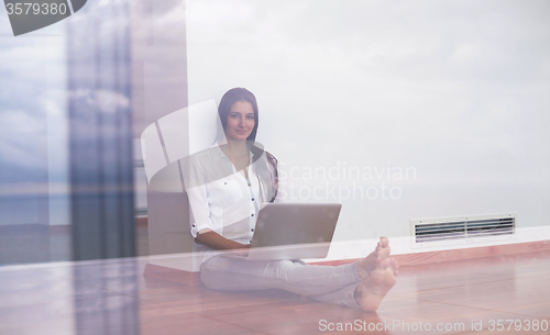 Image of relaxed young woman at home working on laptop computer